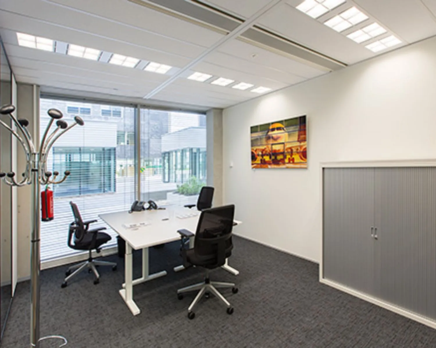 Modern ingerichte kantoorruimte met twee bureaustoelen, een groot raam en een vliegtuigfoto aan de muur.