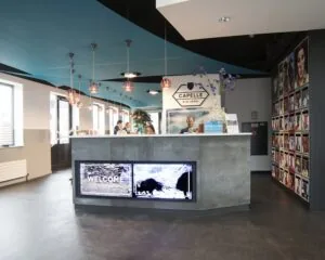 Moderne receptiebalie met digitale schermen en mensen in gesprek in het gemeentehuis van Capelle aan den IJssel.