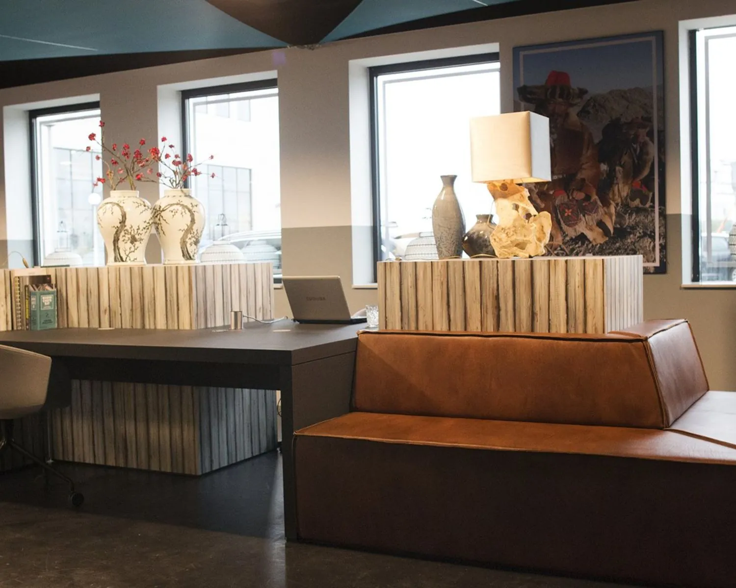 Moderne kantoorruimte met houten accenten, leren banken, decoratieve vazen en tafellampen.