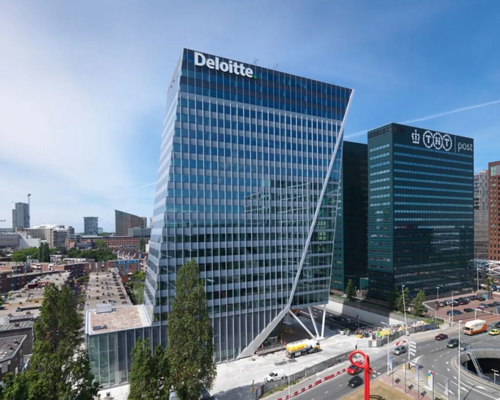 Modern kantoorgebouw van Deloitte met glazen gevel in een stedelijke omgeving.