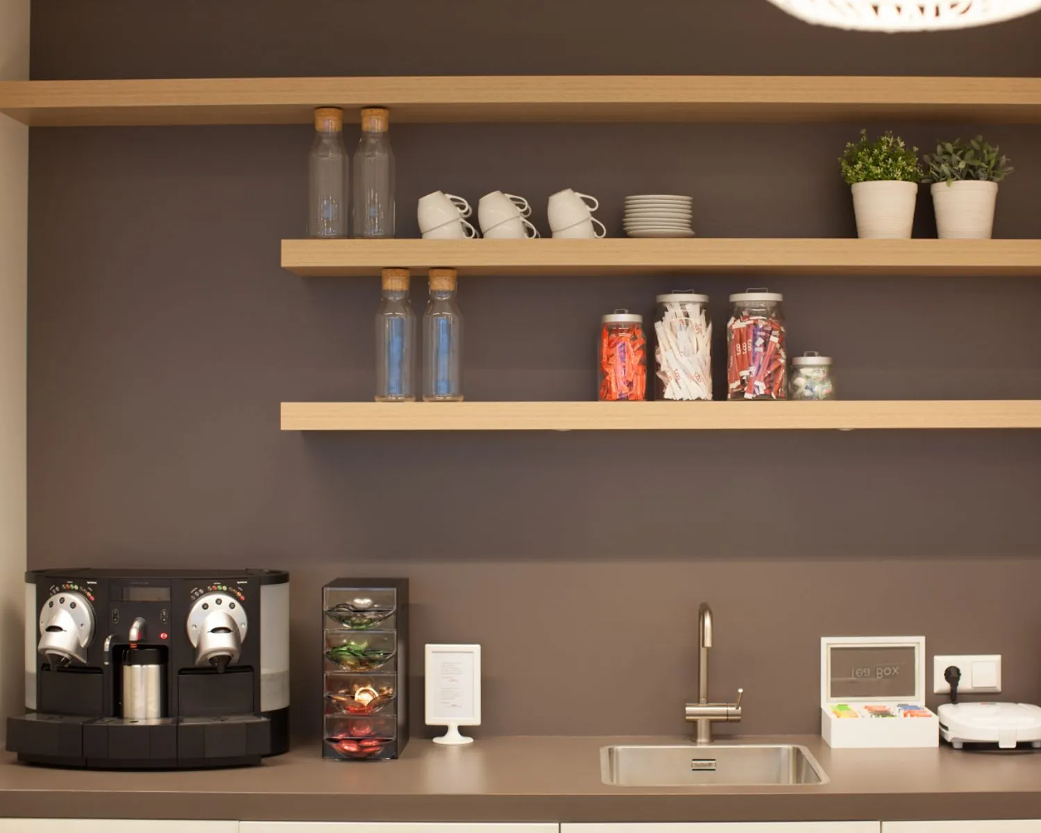 Moderne koffiehoek met een espressomachine, open houten wandplanken en een spoelbak.
