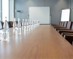 Lange vergadertafel met waterflessen, glazen en stoelen in een moderne vergaderruimte.