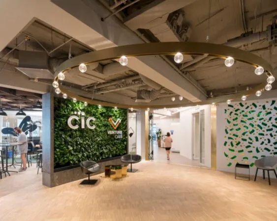 Moderne kantoorlobby van CIC Venture Café met een groene plantenwand, zitgelegenheid en designverlichting.