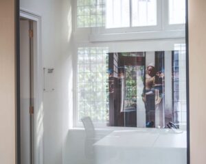 Glazen kantoorruimte met een kunstposter van Vermeers 'Melkmeisje' en kamernummer 2.07 op de muur.