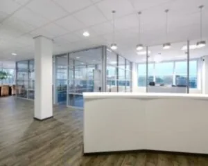 Modern kantoorinterieur met een witte receptiebalie, glazen vergaderruimtes en houten vloer.