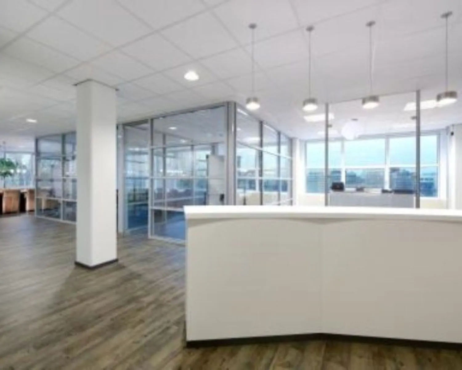 Modern kantoorinterieur met een witte receptiebalie, glazen vergaderruimtes en houten vloer.