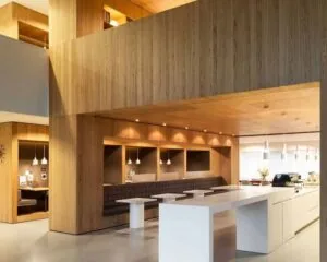 Modern ingerichte kantine met houten wanden, ingebouwde zitnissen en een wit kookeiland met koffiezetapparaat.