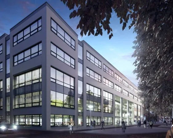 Modern kantoorgebouw met grote ramen en meerdere verdiepingen, omgeven door voetgangers en bomen in de schemering.
