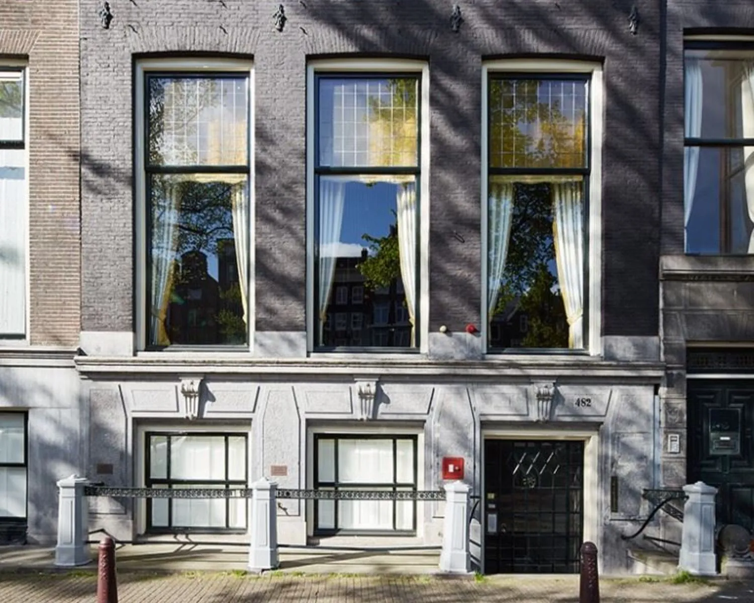 Voorgevel van een historisch grachtenpand aan de Keizersgracht in Amsterdam met grote ramen en een zwarthekwerk.