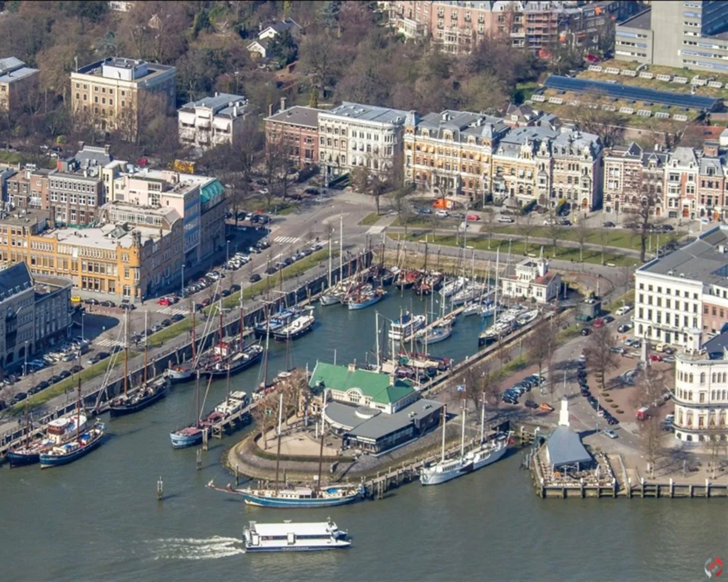Luchtfoto van de Veerhaven in Rotterdam met aangemeerde klassieke schepen en omliggende historische panden.