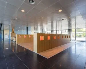 Moderne, open kantoorruimte met houten scheidingswand met verlichte nissen en grote ramen.