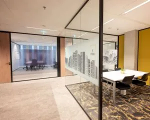 Moderne kantoorruimte met glazen wanden, vergadertafel en wanddecoratie van de skyline van Rotterdam.