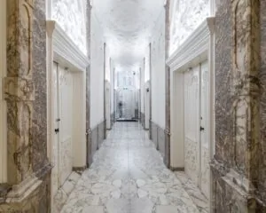 Luxe marmeren gang met decoratief stucwerk en dubbele deuren in een klassiek ingericht gebouw.