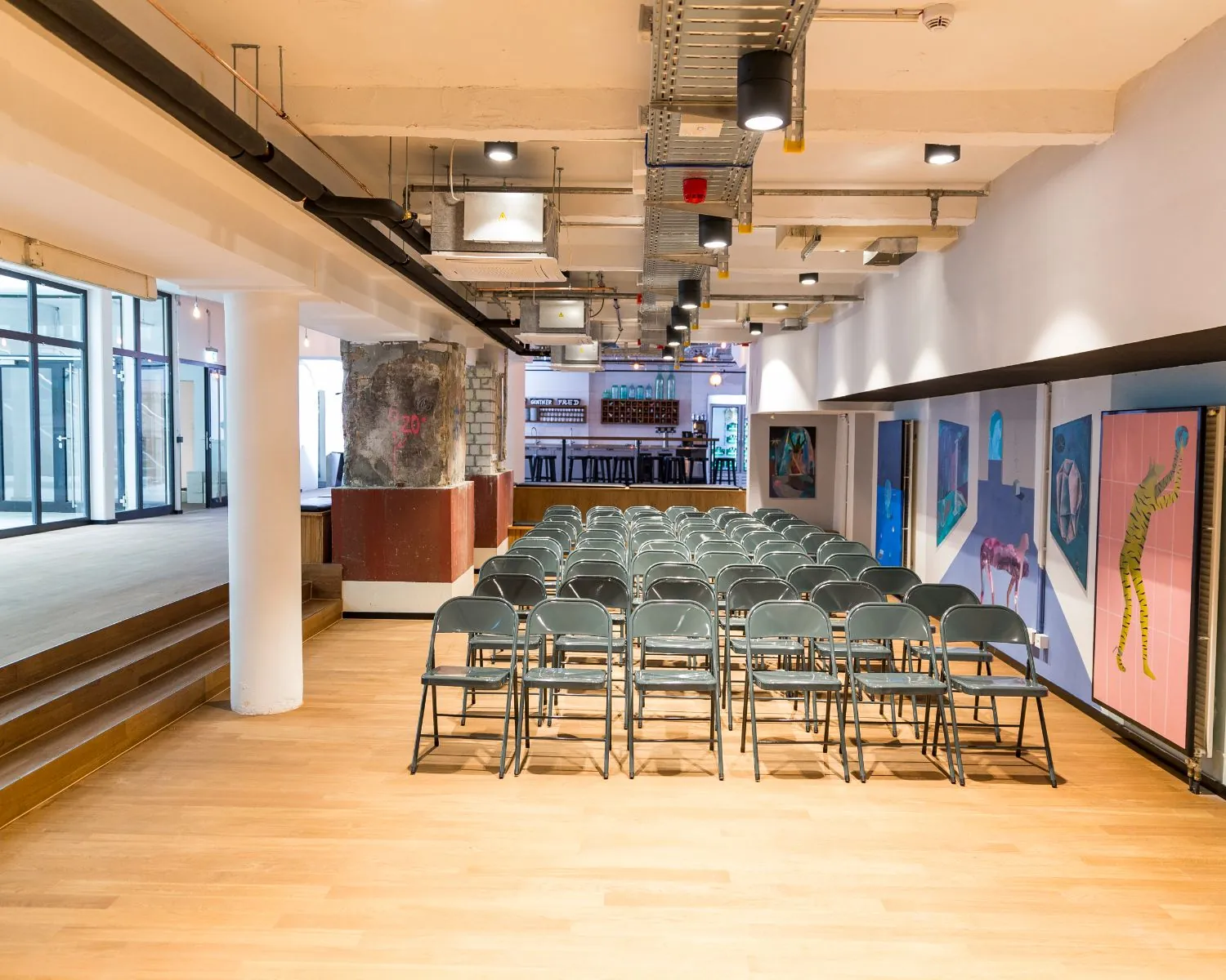 Opgestelde rijen met klapstoelen in een moderne, industriële evenementenruimte met kunst aan de muur.