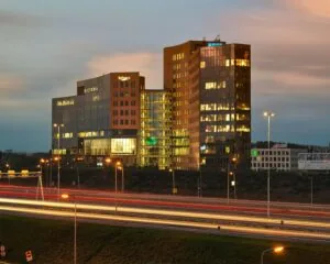 Kantoorgebouw Victoria met lichtsporen van voorbijrijdend verkeer langs de snelweg bij schemering.