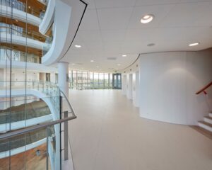Ruim en modern ingericht kantoorgebouw met glazen balustrades en grote raampartijen.