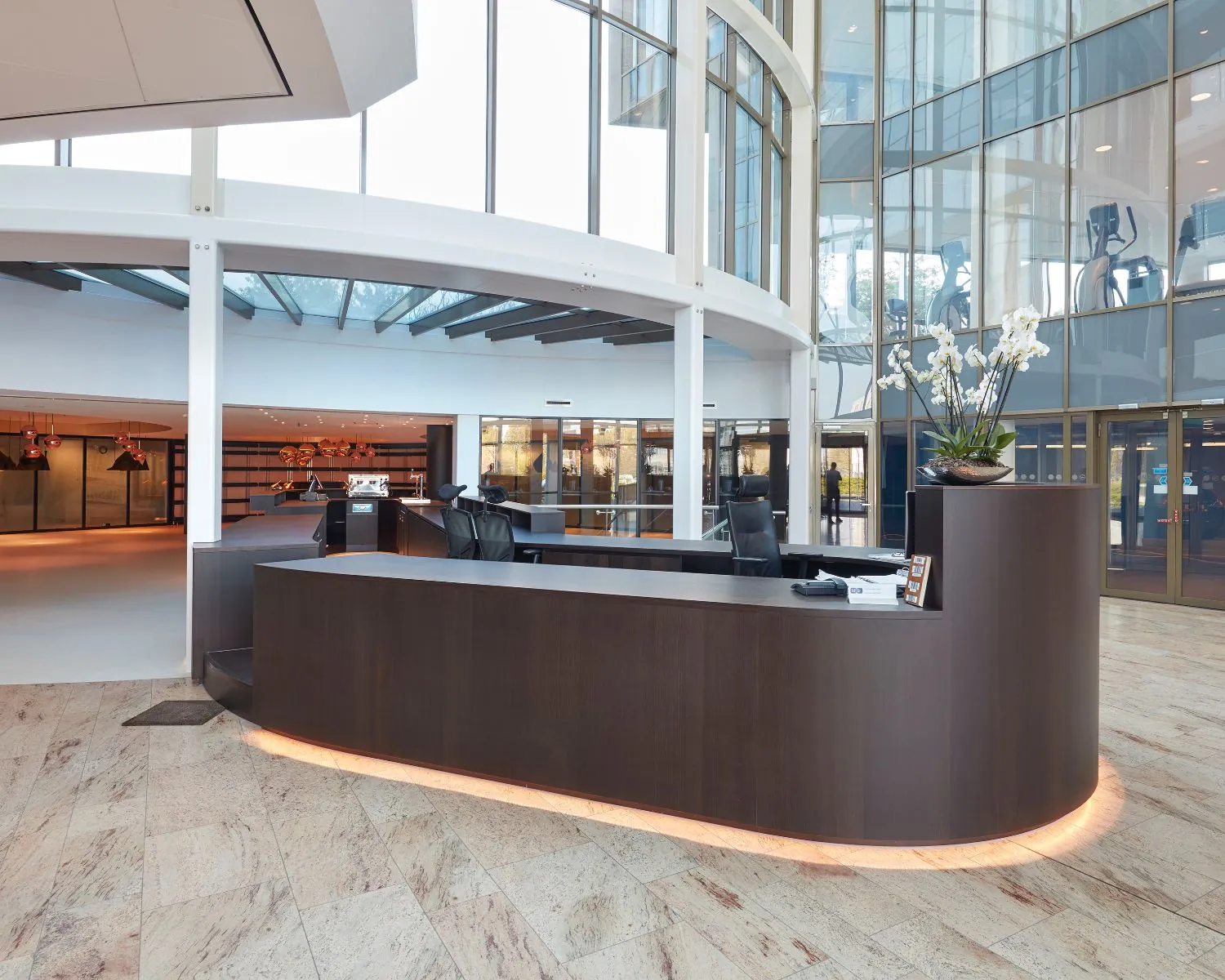 Moderne receptiebalie in een lichte, ruime entreehal met grote glazen ramen en een strakke afwerking.