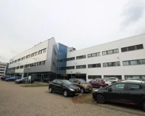 Moderne kantoorgebouwen met een parkeerplaats vol geparkeerde auto’s aan de voorzijde.