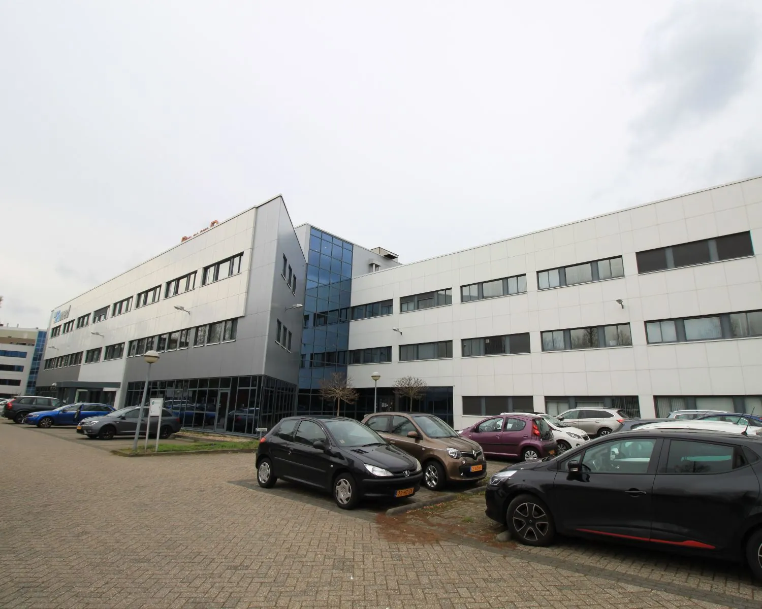 Moderne kantoorgebouwen met een parkeerplaats vol geparkeerde auto’s aan de voorzijde.