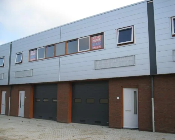 Bedrijfsunits met grijze gevelbekleding en "Te Huur" borden op de ramen.
