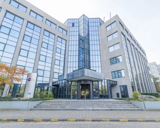 Vooraanzicht van een modern kantoorgebouw met glazen gevel en het bord van NGA Human Resources bij de ingang.