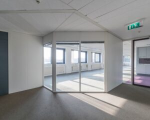 Lichte, moderne kantoorruimte met glazen tussenwand en grote ramen.