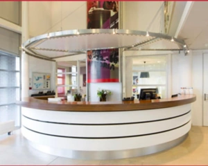 Balie met houten blad en moderne witte afwerking in een helder verlichte ontvangstruimte.