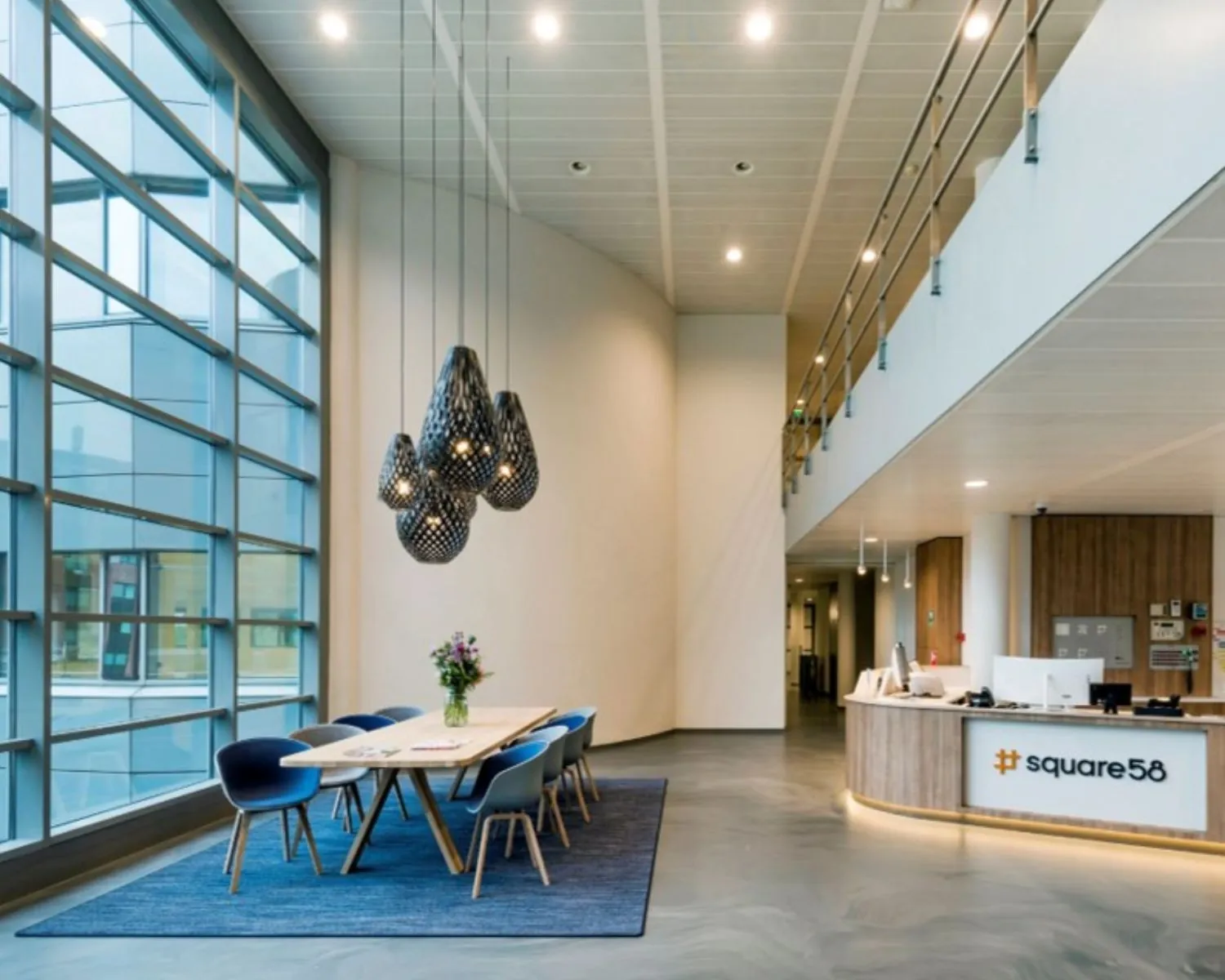 Moderne kantoorinrichting met vergadertafel, designverlichting en receptiebalie van Square58.