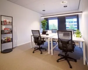 Moderne en lichte kantoorruimte met vier bureaus, ergonomische stoelen, laptops, kamerplanten en een tijdschriftenrek met onder andere Vogue en LINDA.
