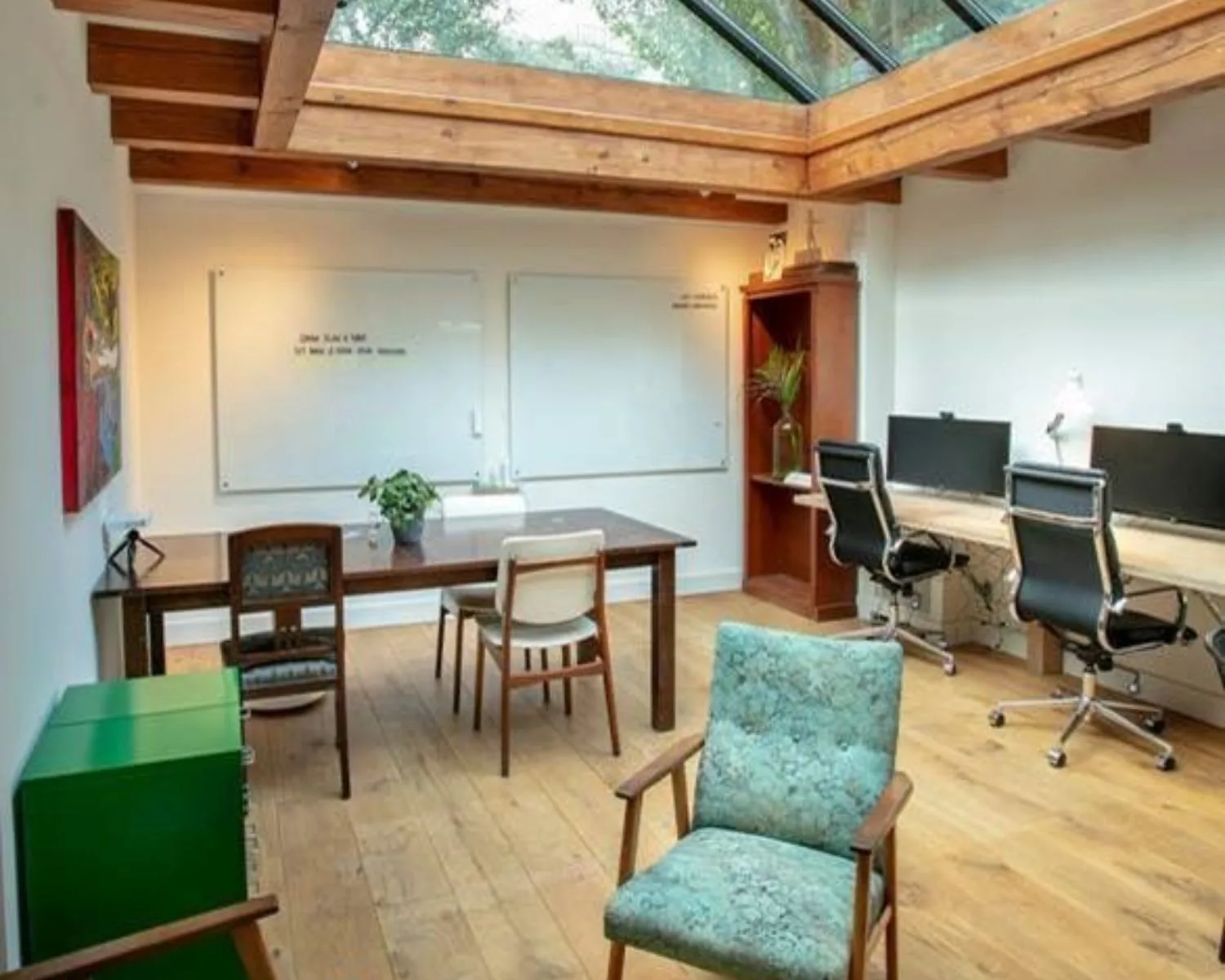 Modern kantoor met houten vloer, dakramen en een mix van vintage en moderne meubels.