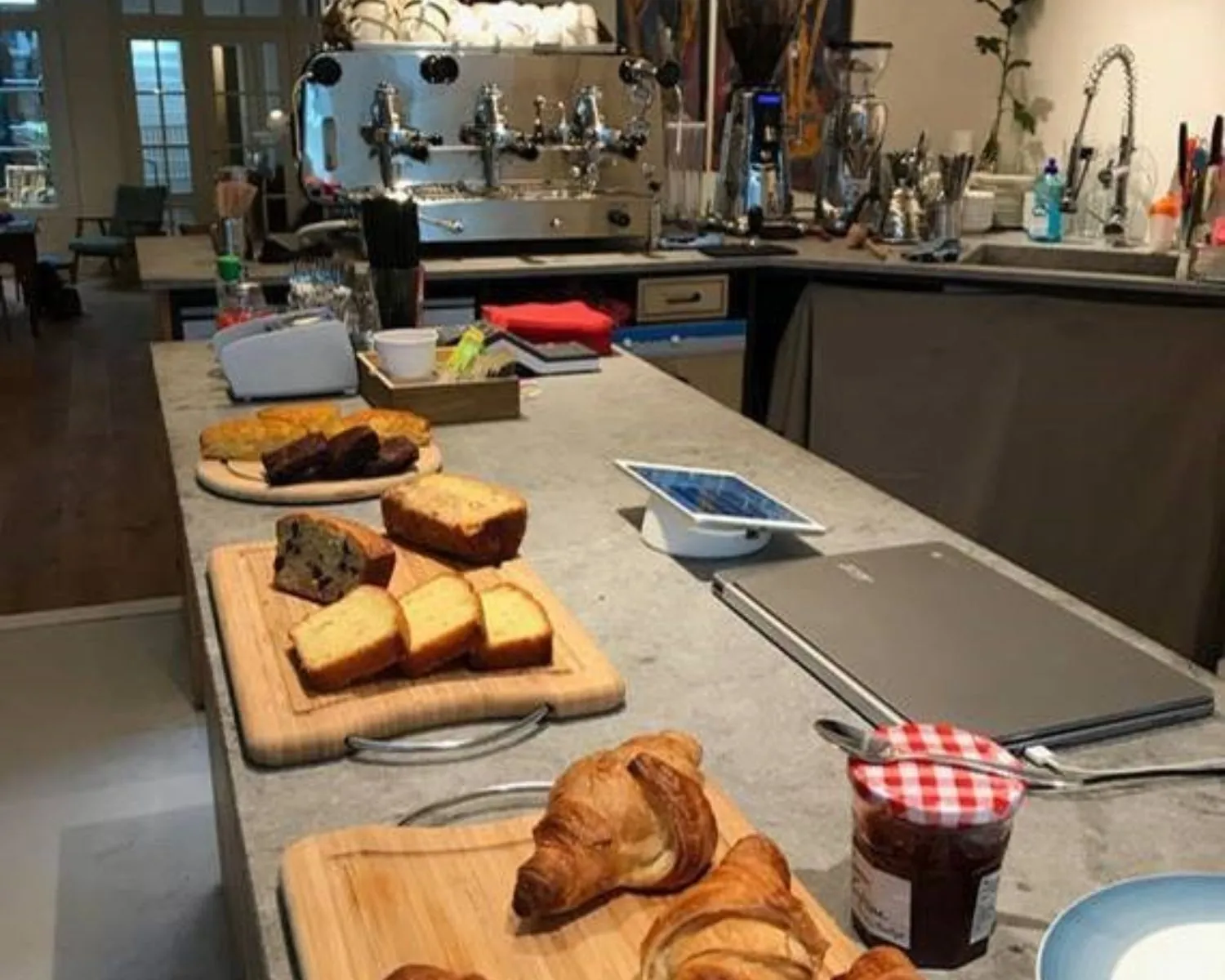 Ontbijt met croissants, cake, jam en koffie in een moderne koffiekeuken.