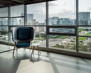 Designstoel en bijzettafeltje bij een raam met uitzicht op moderne kantoorgebouwen en een kruispunt in de stad.