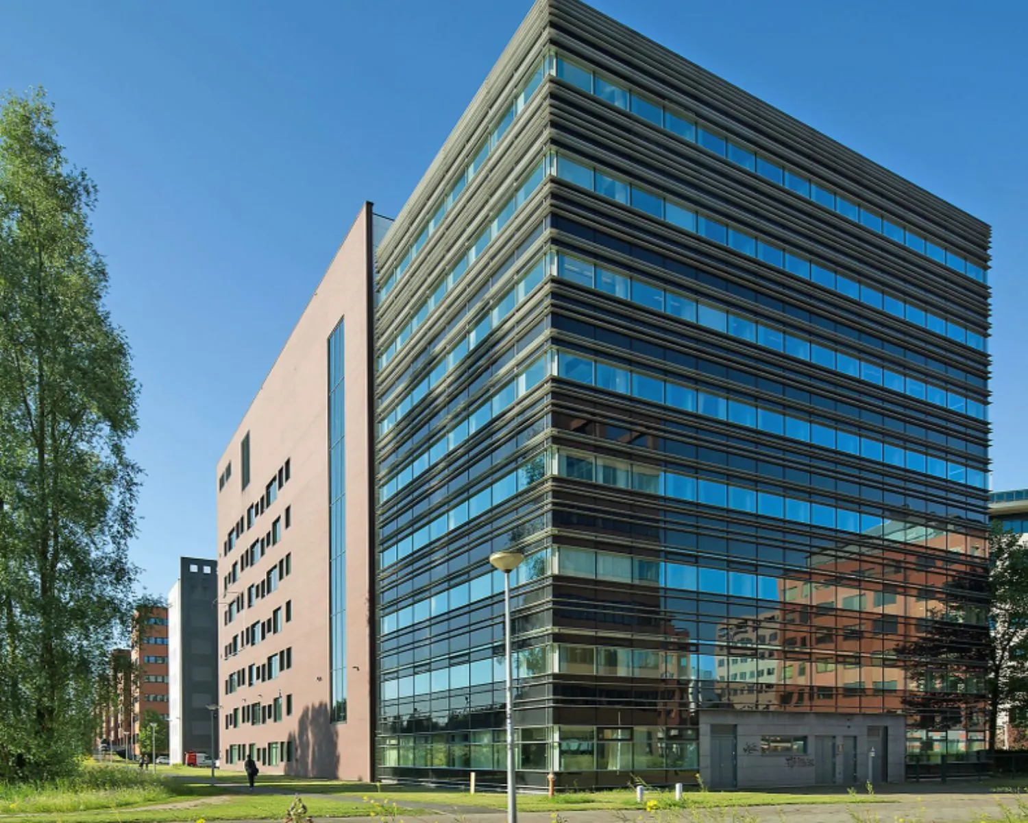 Modern kantoorgebouw met glazen gevels en een strakke architectuur onder een heldere blauwe lucht.