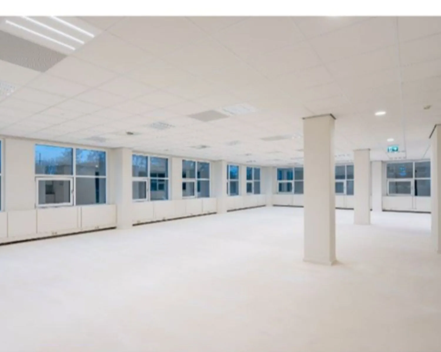 Licht en ruim leegstaand kantoorpand met grote ramen en systeemplafond.