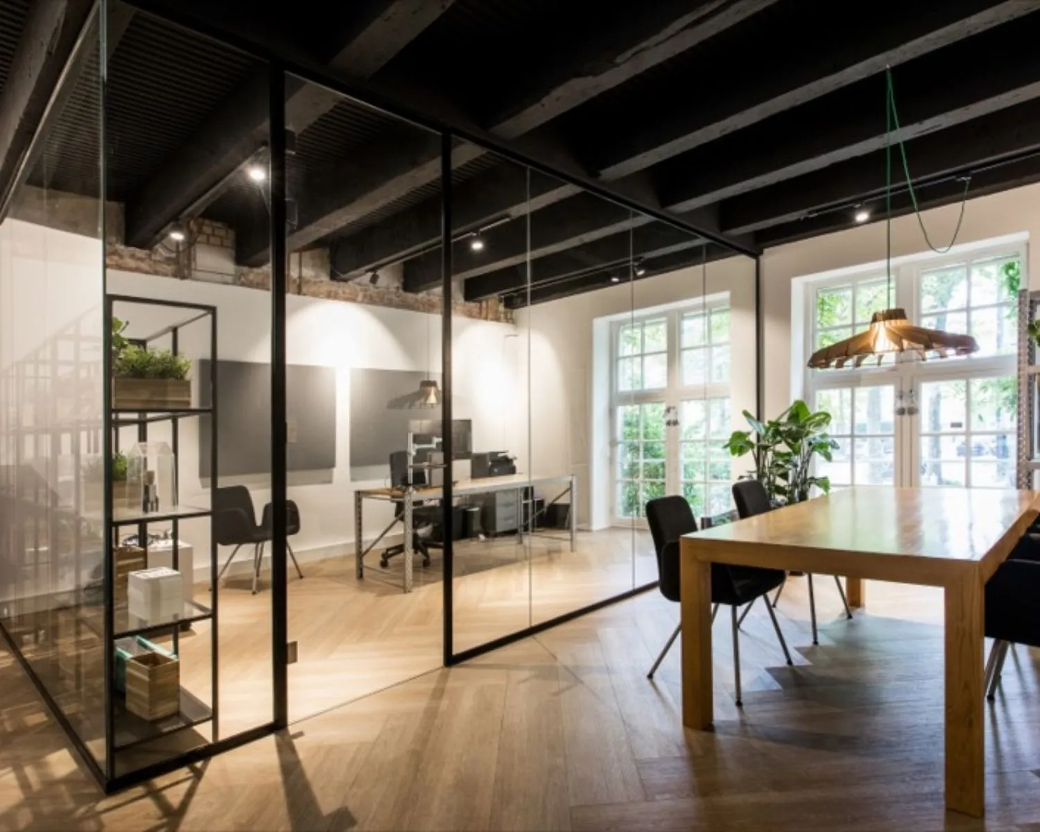 Modern kantoorinterieur met glazen vergaderruimte, houten vloer, grote ramen en industriële details.