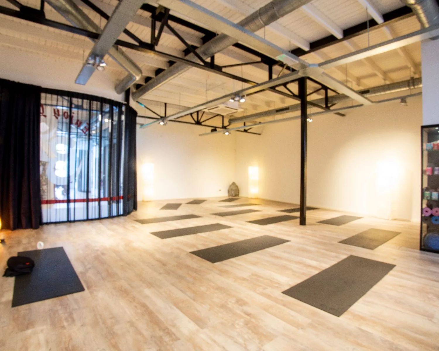 Lichte en moderne yogastudio met uitgerolde yogamatten op een houten vloer.