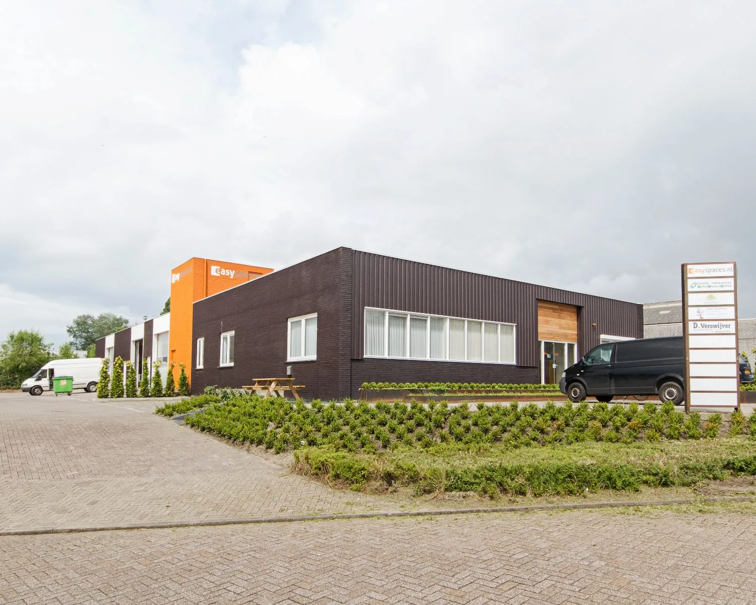 Bedrijfsgebouw van Easyspaces.nl met moderne gevel en geparkeerde bestelwagens op de voorgrond.
