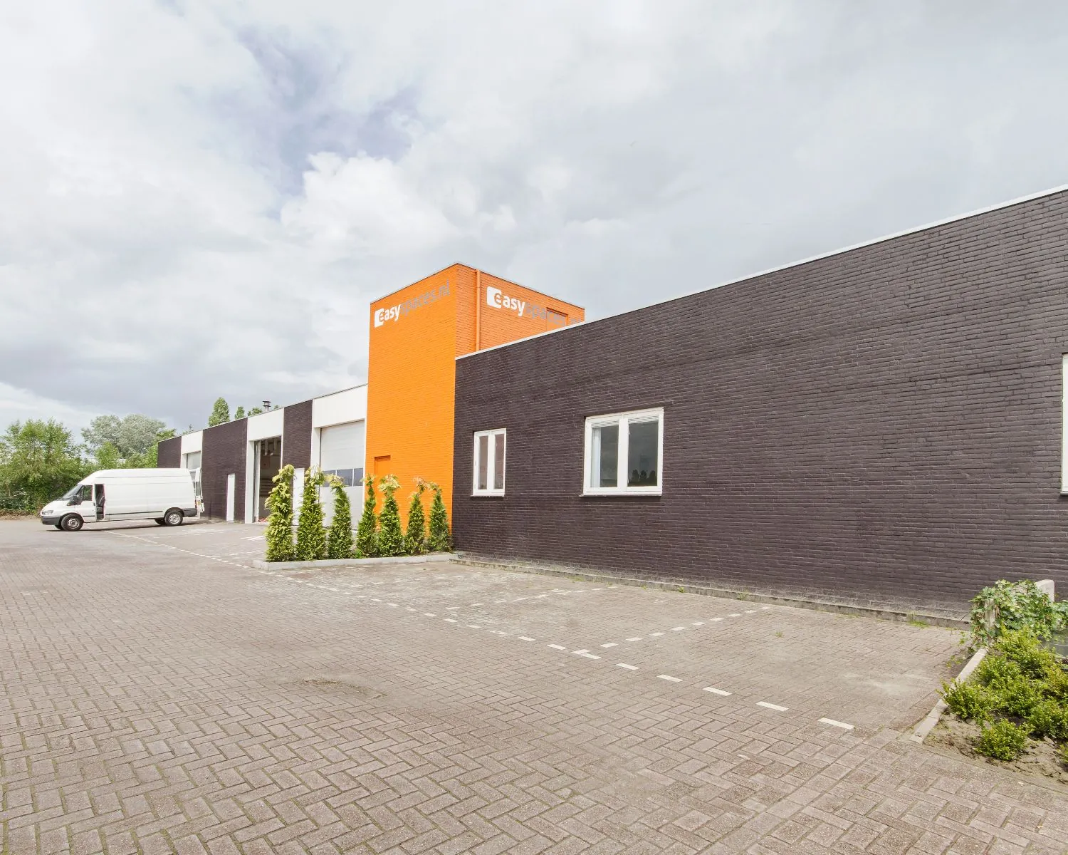 Bedrijfsgebouw van Easy Parts met oranje gevel en parkeerplaats op de voorgrond.