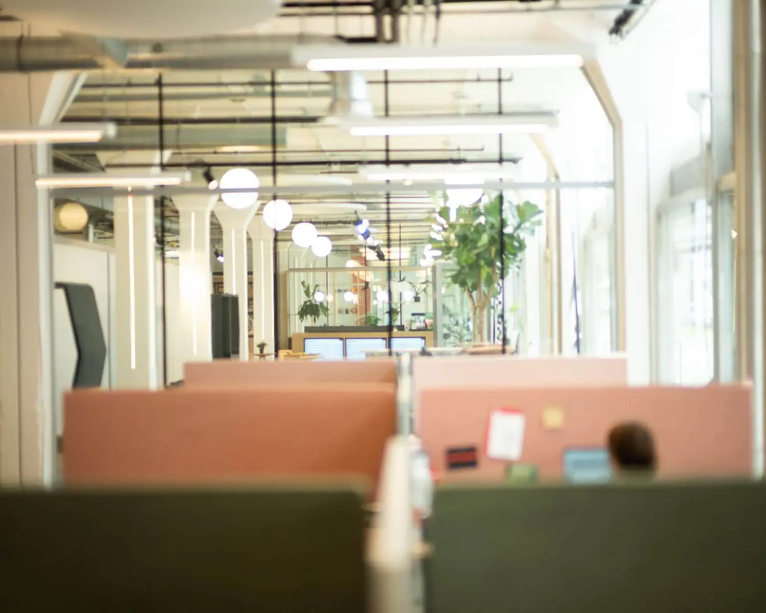 Open kantoorruimte met gestoffeerde werkplekken, laptops en moderne verlichting.