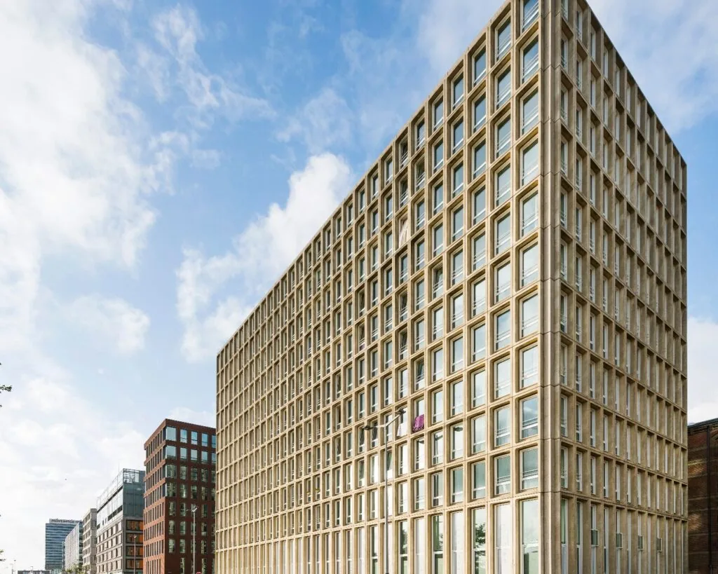 Modern rechthoekig kantoorgebouw met een gevel van betonnen raamkozijnen in een stedelijke omgeving.