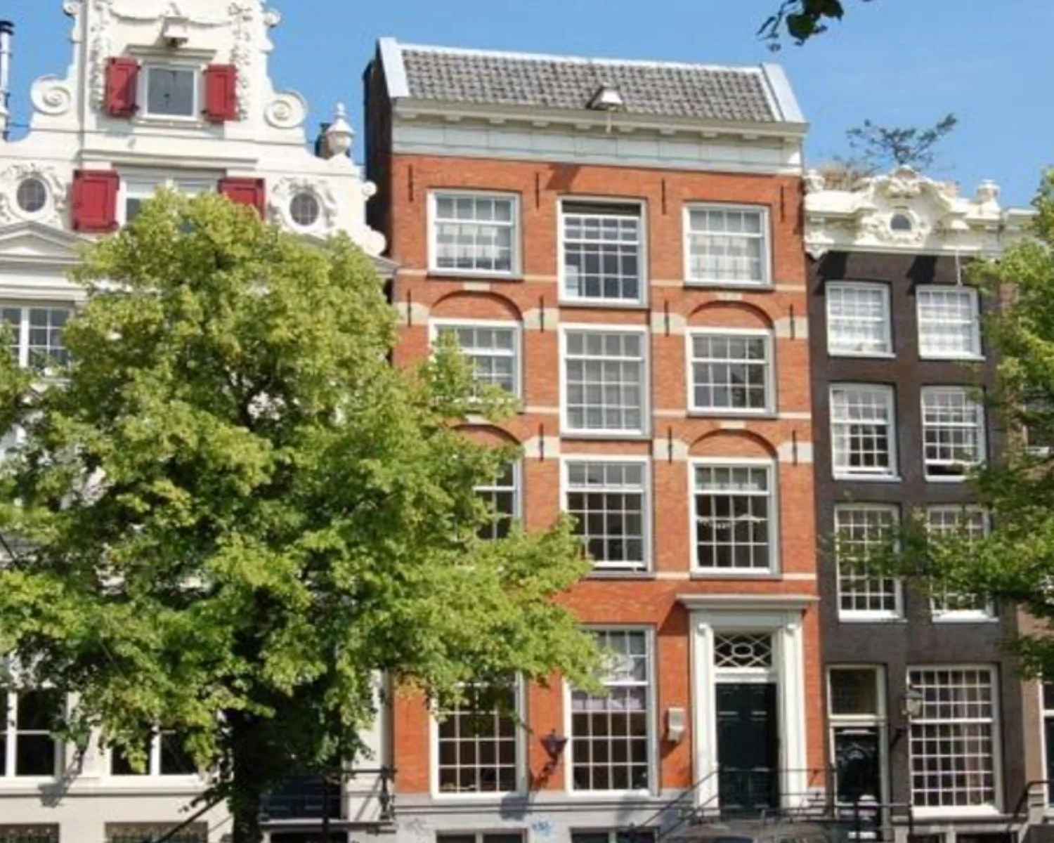 Gevel van het Anne Frank Huis in Amsterdam, omringd door historische panden en bomen.