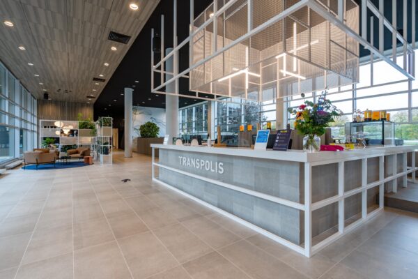 Moderne, ruime lobby van Transpolis met een stijlvolle receptiebalie en zitgedeelte.