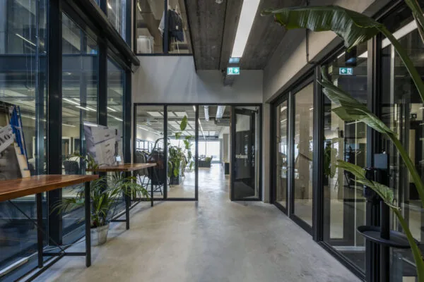 Moderne kantoorruimte aan de Danzigerkade met glazen wanden, betonnen plafond en veel groen.