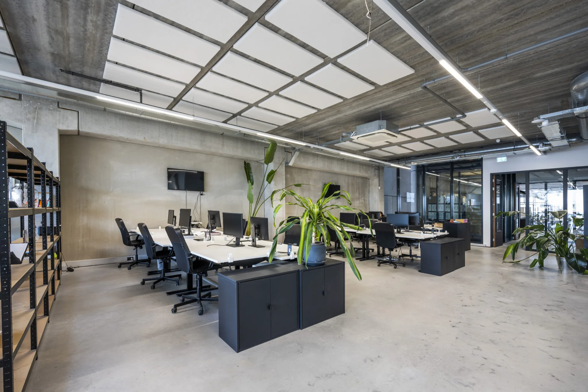 Modern industrieel kantoorinterieur aan de Danzigerkade met open werkplekken, planten en betonnen afwerking.