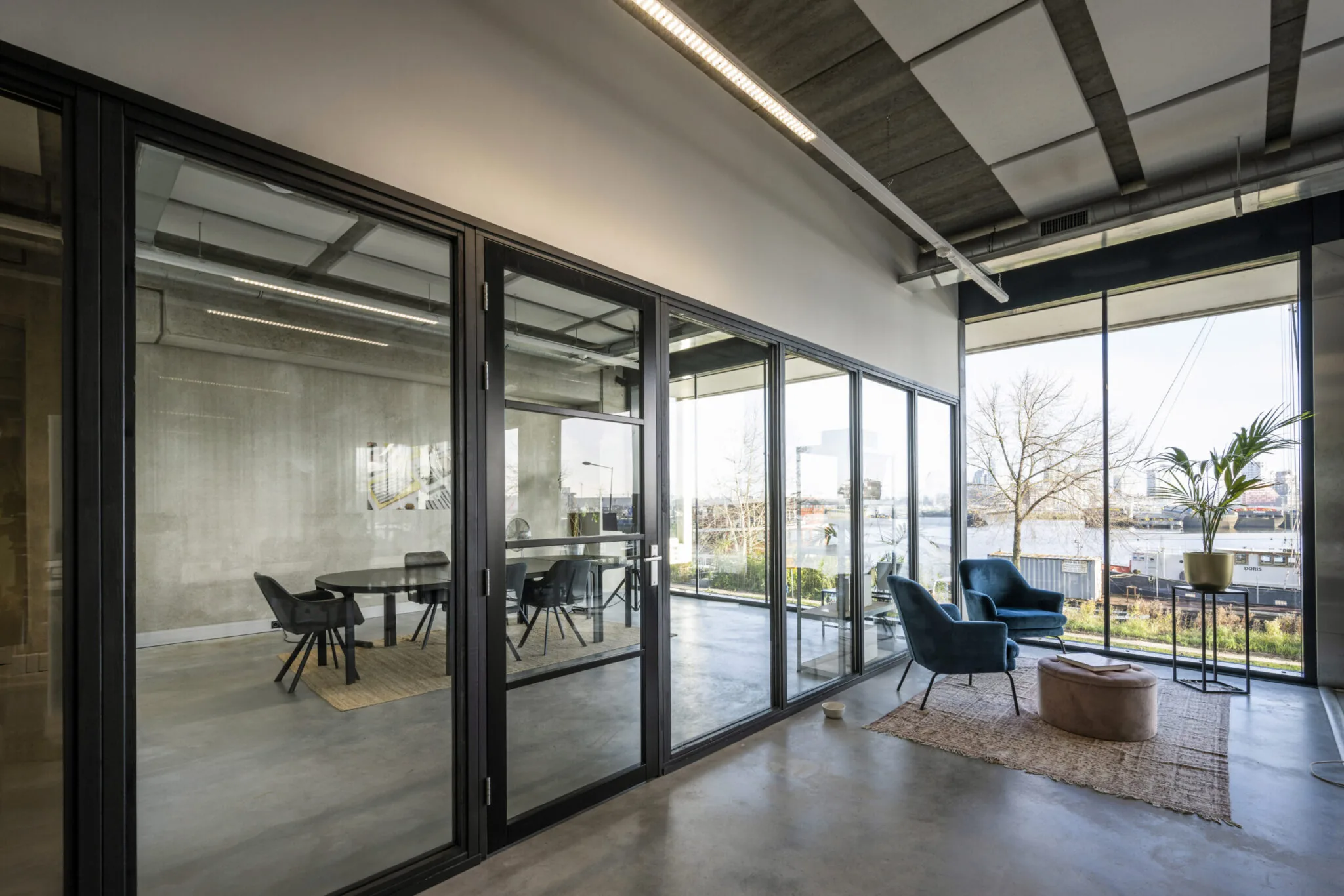 Modern kantoorinterieur aan de Danzigerkade met glazen vergaderruimte en zitgedeelte met uitzicht op het water.