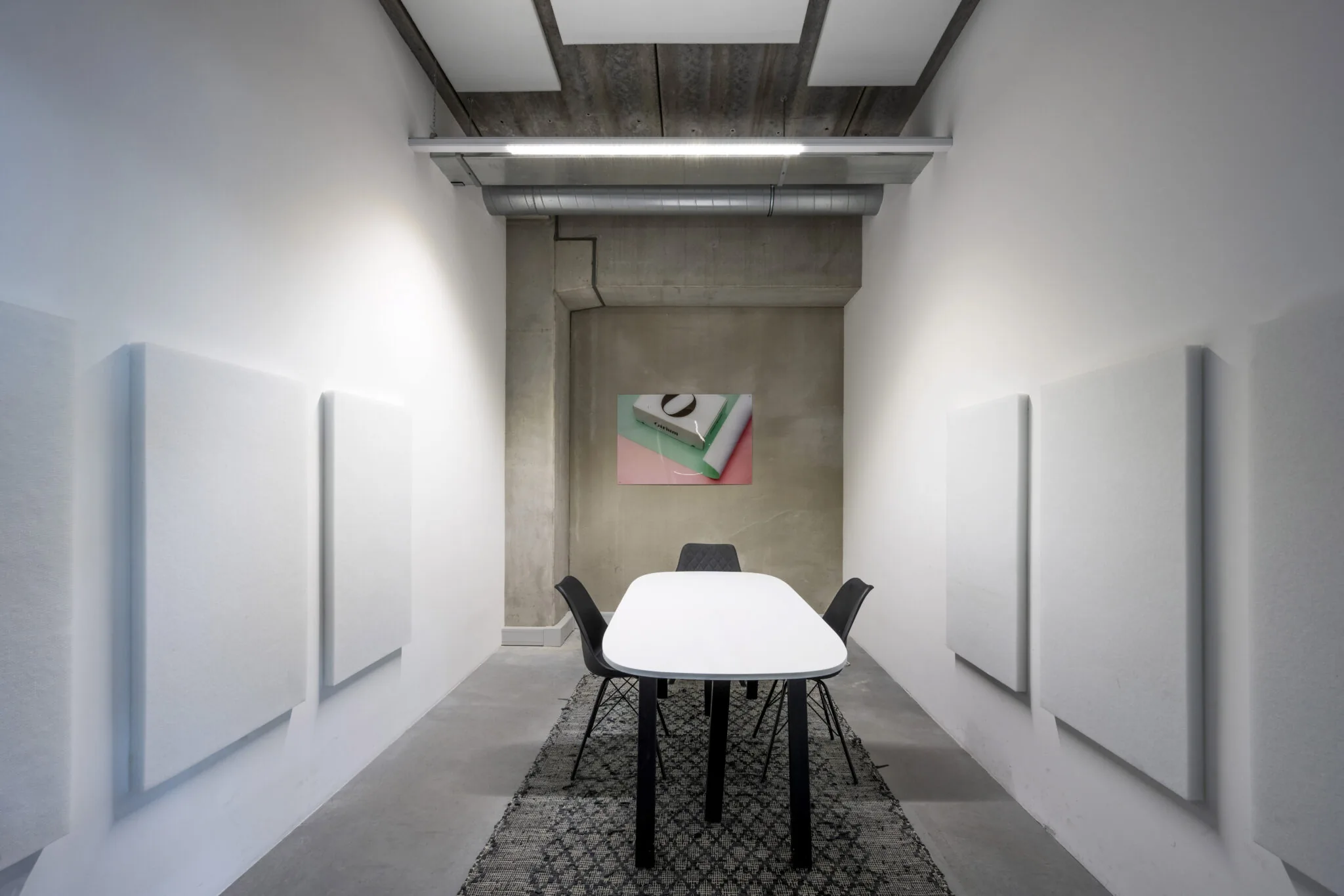 Vergaderruimte aan de Danzigerkade met witte tafel, zwarte stoelen, akoestische panelen en kunstwerk van Paul Starink aan de muur.