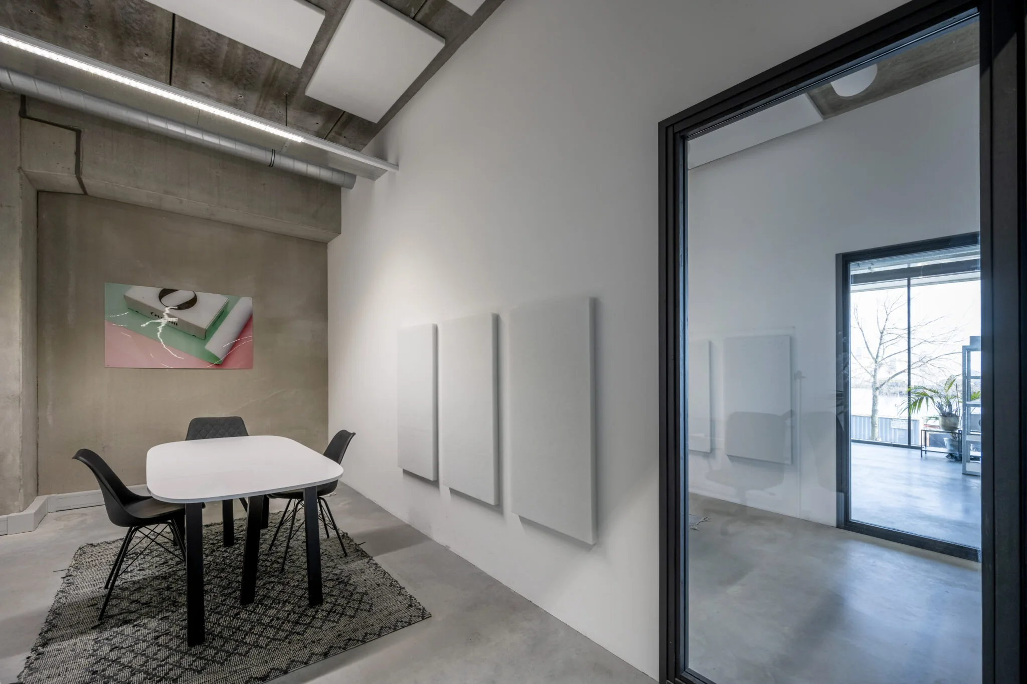 Moderne vergaderruimte met betonnen muren, een witte tafel en zwart meubilair in het kantoor aan de Danzigerkade 024 van Paul Starink.