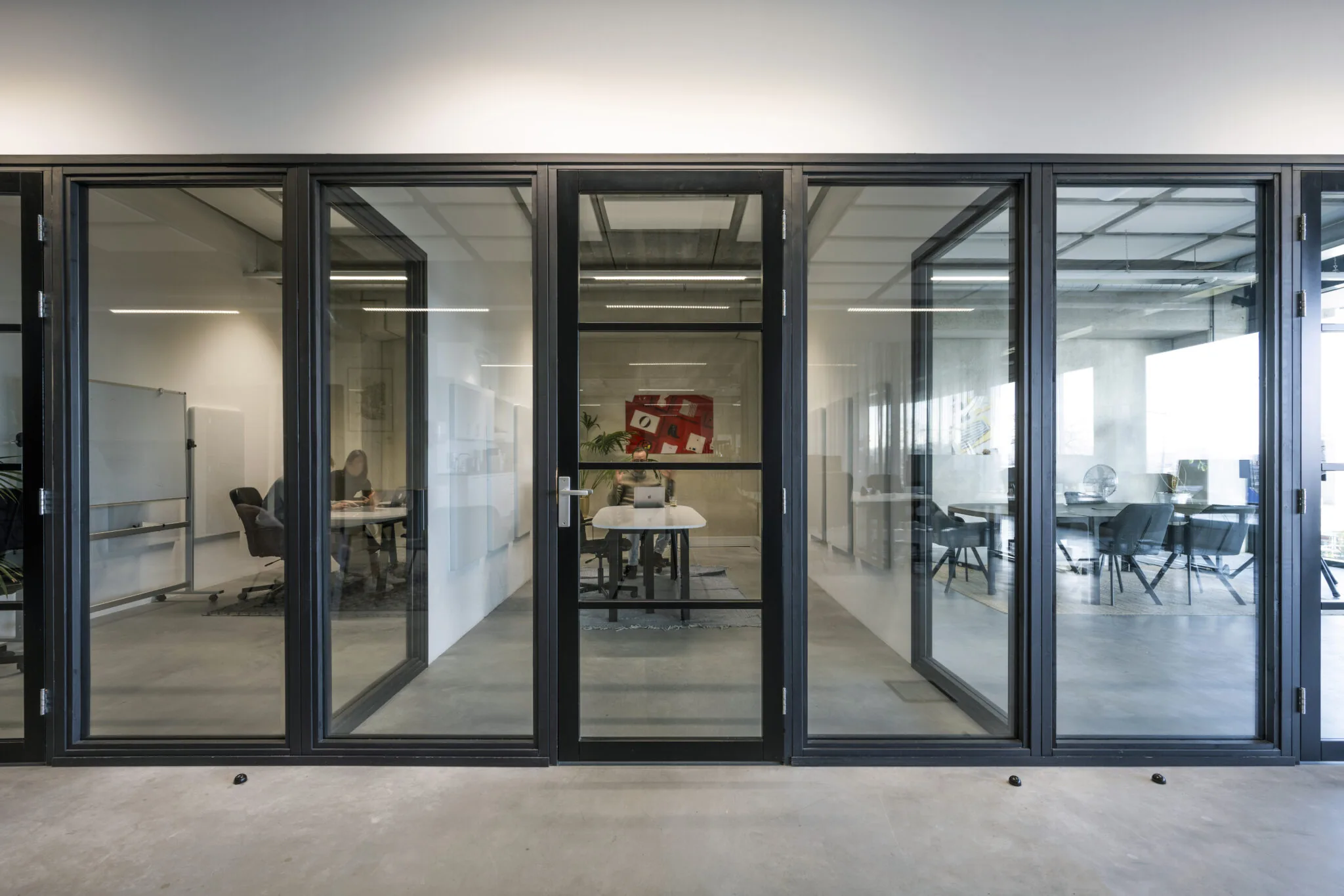 Moderne kantoorruimte aan de Danzigerkade met glazen wanden en zicht op meerdere vergaderruimtes.
