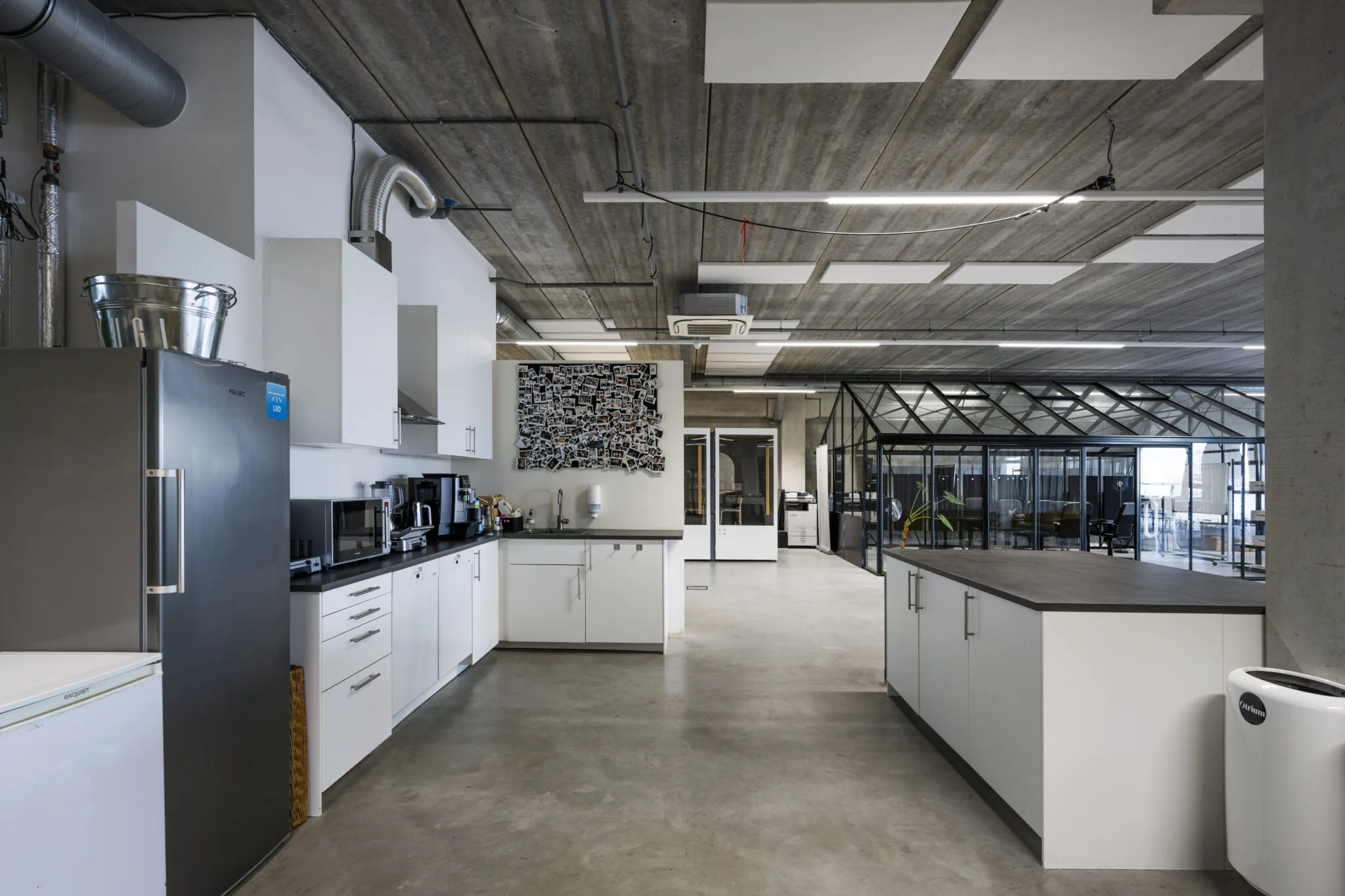 Moderne kantoorkeuken met witte kasten, koffieapparaten en zicht op een glazen vergaderruimte bij Danzigerkade 030.