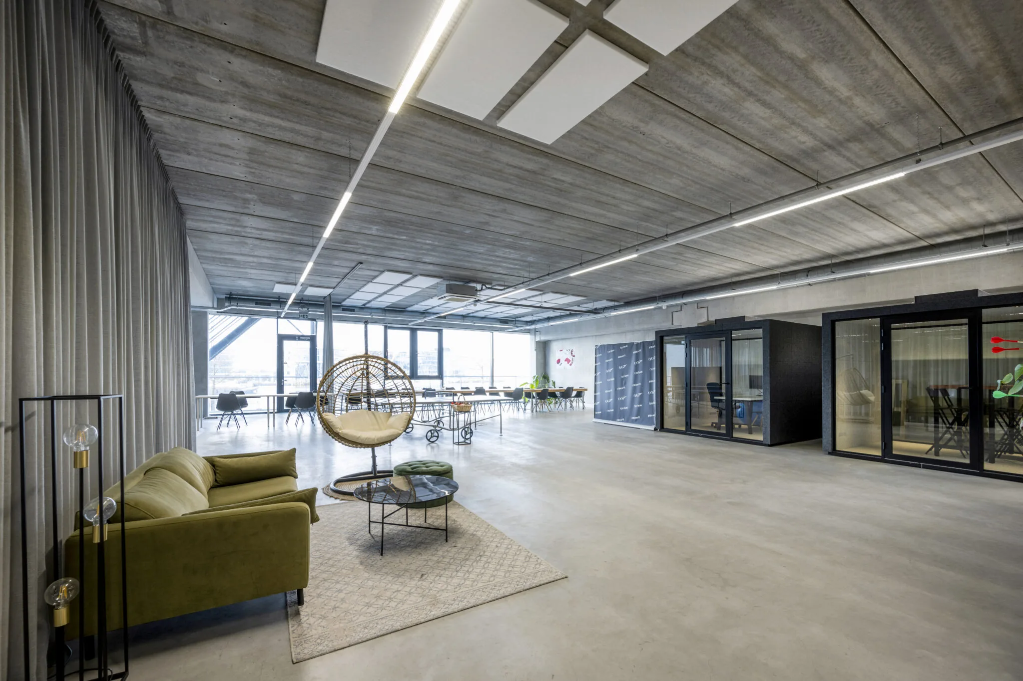 Moderne, ruimtelijke kantoorruimte aan de Danzigerkade met zithoek, vergadertafels en glazen werkcabines.